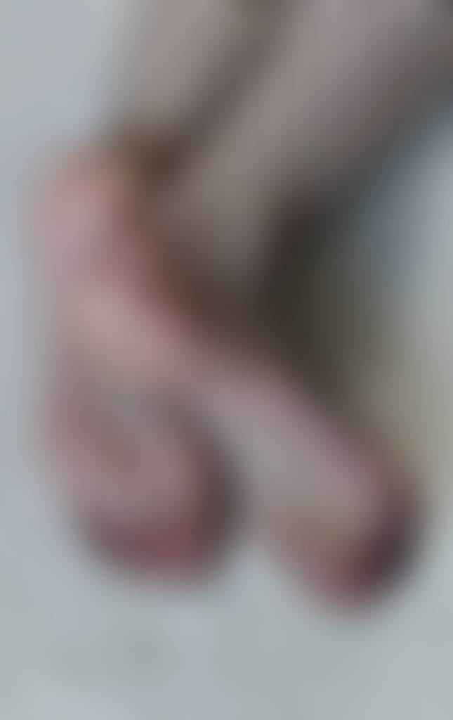 Her feet, wrapped in delicate fishnet, reveal a soft, teasing elegance—where texture and s